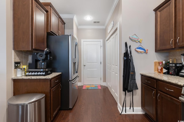 kitchen featuring decorative backsplash, light stone countertops, ornamental molding, dark wood-type flooring, and stainless steel fridge with ice dispenser