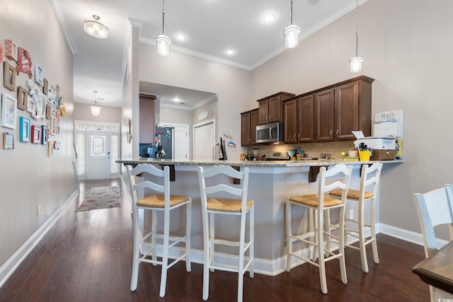 kitchen featuring kitchen peninsula, light stone counters, and hanging light fixtures