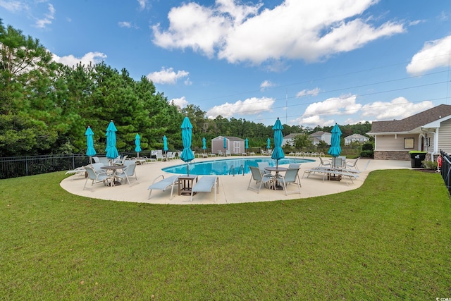 view of pool with a lawn and a storage shed