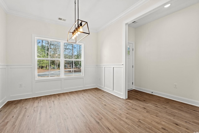 unfurnished dining area featuring ornamental molding, light hardwood / wood-style flooring, and an inviting chandelier