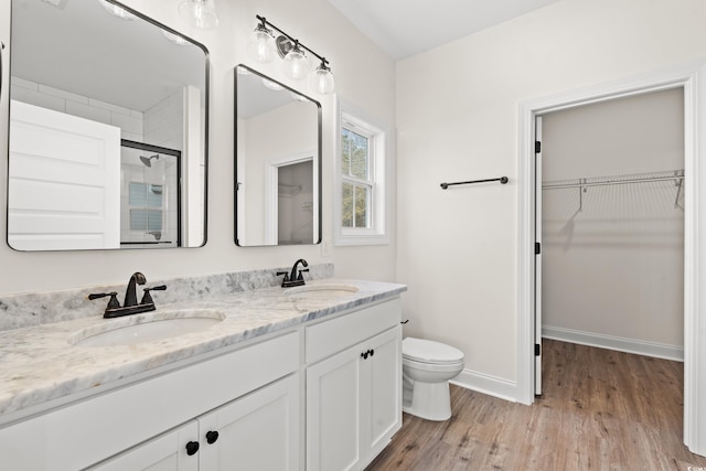 bathroom featuring toilet, vanity, a shower with shower door, and hardwood / wood-style flooring