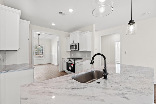 kitchen featuring appliances with stainless steel finishes, white cabinetry, hanging light fixtures, and sink