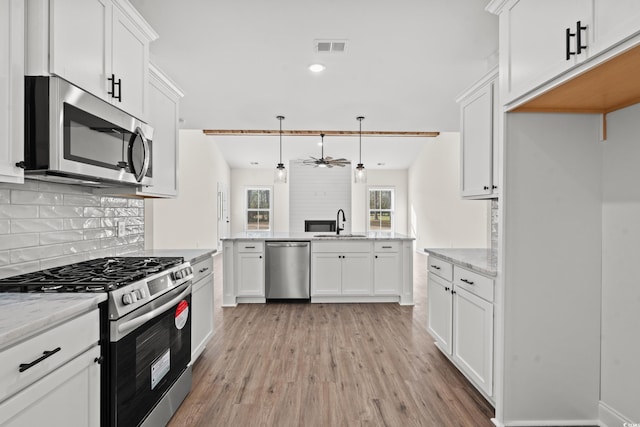 kitchen with ceiling fan, light stone countertops, decorative light fixtures, white cabinetry, and stainless steel appliances