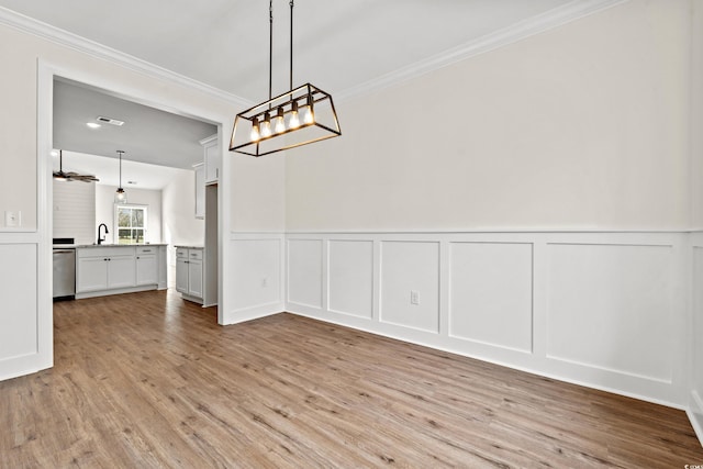 unfurnished dining area with crown molding, light wood-type flooring, and sink