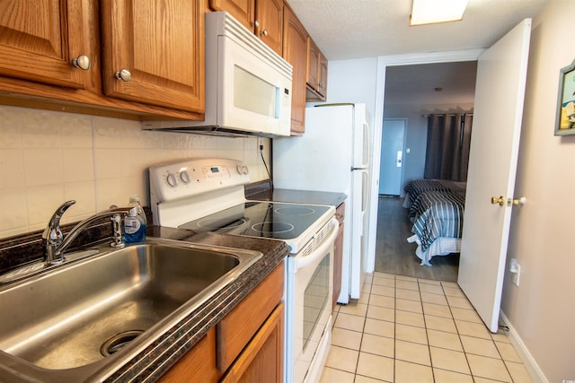 kitchen featuring light tile patterned floors, white appliances, tasteful backsplash, and sink