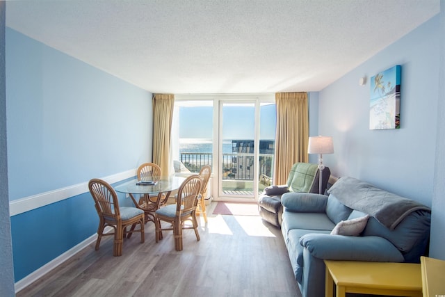 living room featuring hardwood / wood-style floors, expansive windows, a water view, and a textured ceiling