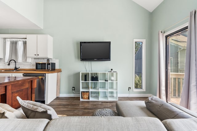 living room with dark hardwood / wood-style flooring, sink, and high vaulted ceiling