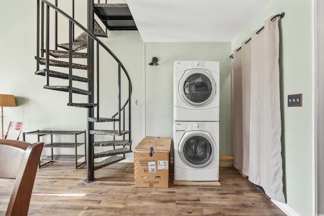 laundry room featuring stacked washer and dryer and wood-type flooring