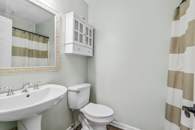 bathroom featuring a shower with curtain, toilet, and sink