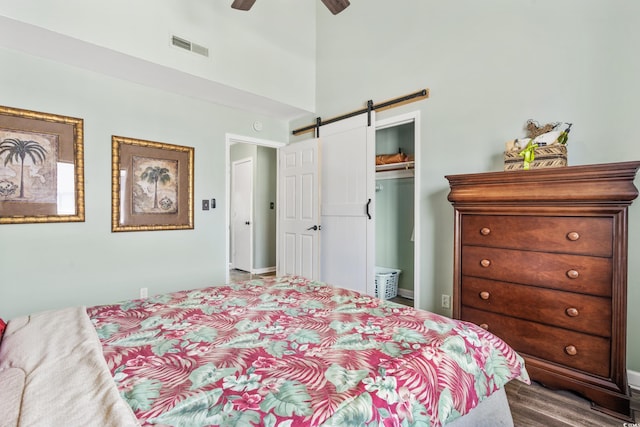 bedroom with a barn door, ceiling fan, a closet, and a high ceiling