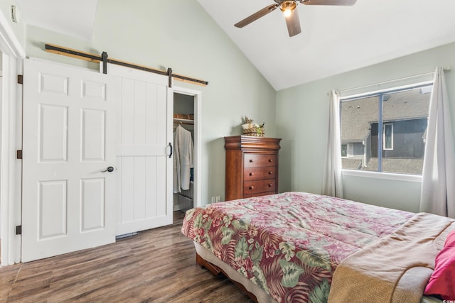 bedroom featuring ceiling fan, a barn door, dark hardwood / wood-style flooring, and vaulted ceiling