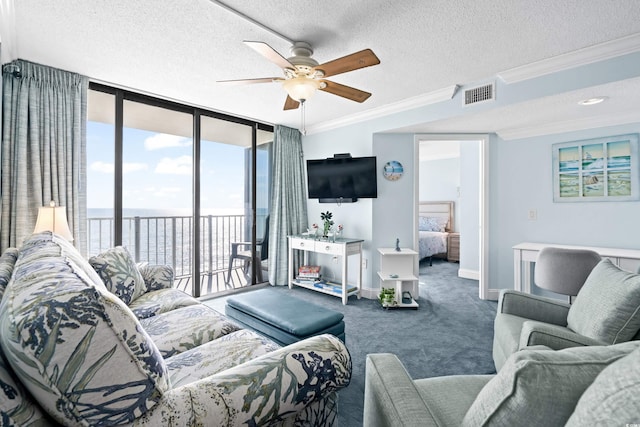 carpeted living room with ceiling fan, expansive windows, a textured ceiling, and ornamental molding