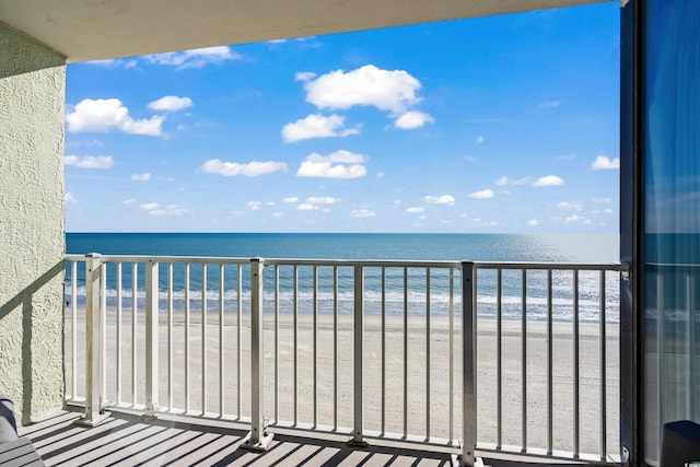 balcony with a water view and a view of the beach