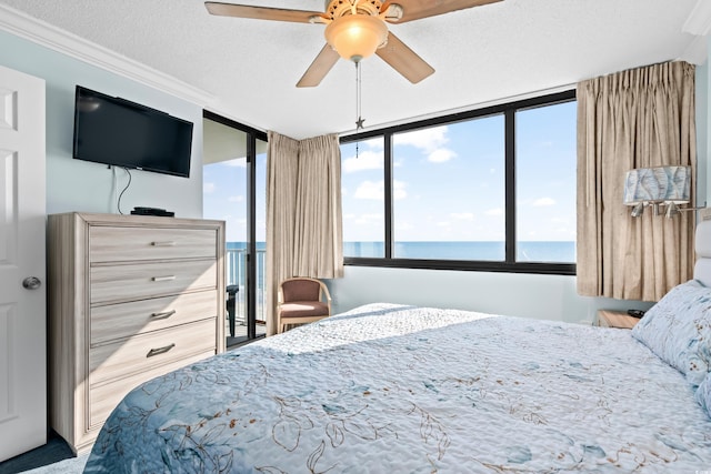 bedroom with a textured ceiling, a water view, ceiling fan, and crown molding