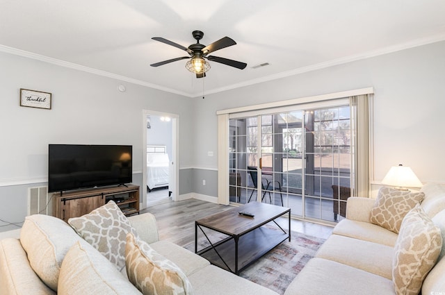 living room featuring ceiling fan, light wood-type flooring, and crown molding