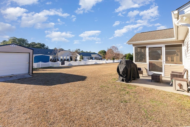 view of yard with an outbuilding, a patio, a sunroom, and a garage