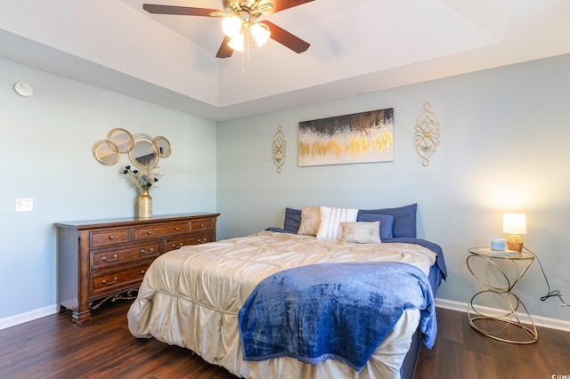 bedroom with dark hardwood / wood-style flooring, a raised ceiling, and ceiling fan