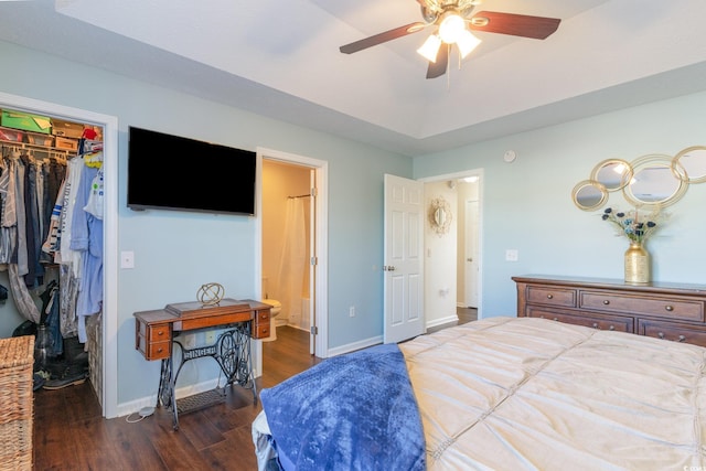 bedroom featuring dark wood-type flooring, ceiling fan, connected bathroom, a walk in closet, and a closet