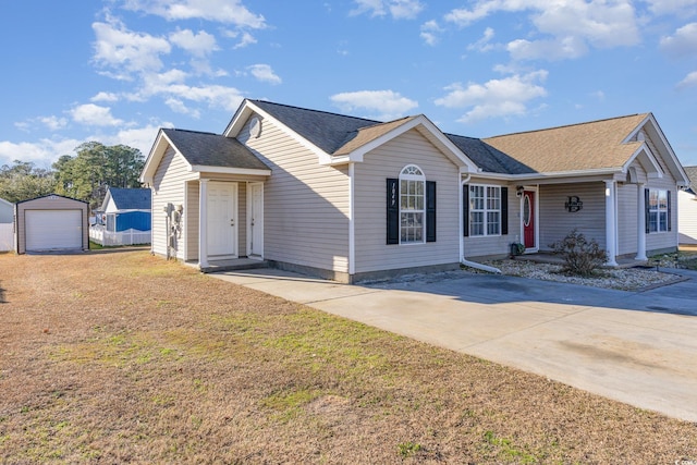 single story home with a garage, an outbuilding, and a front yard