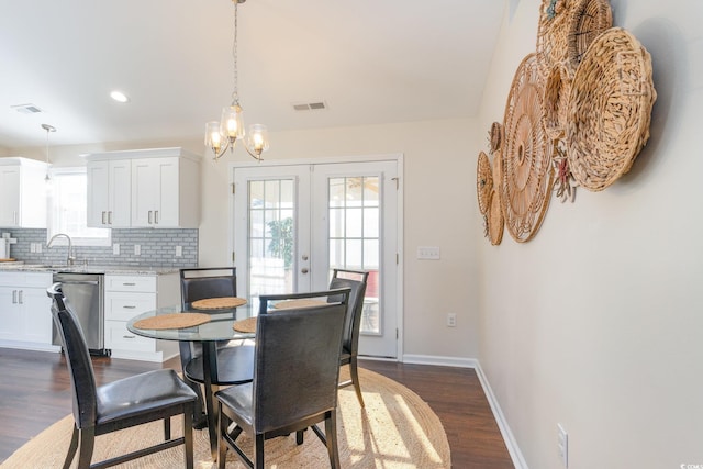 dining area with sink, a chandelier, dark hardwood / wood-style flooring, and french doors