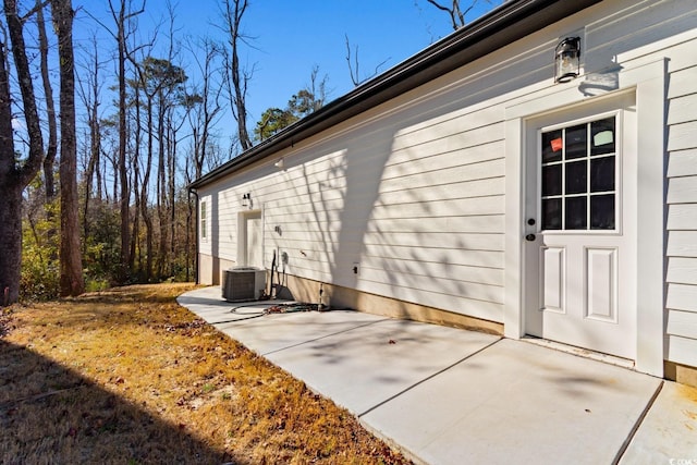 view of exterior entry with a patio and central AC