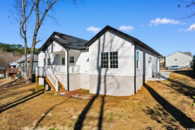 view of property exterior with covered porch, a yard, and central AC