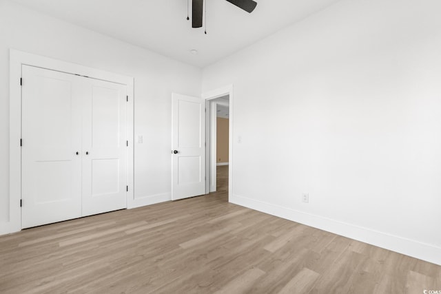 unfurnished bedroom featuring ceiling fan, a closet, and light hardwood / wood-style flooring