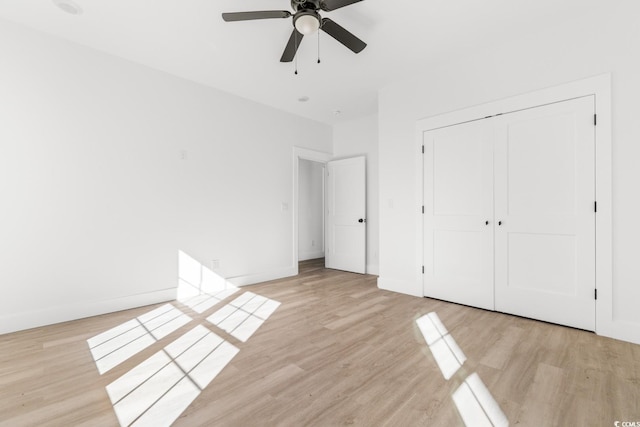 unfurnished bedroom with ceiling fan, a closet, and light wood-type flooring