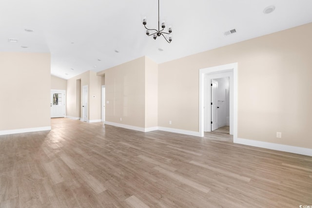 unfurnished living room featuring a notable chandelier and light hardwood / wood-style floors