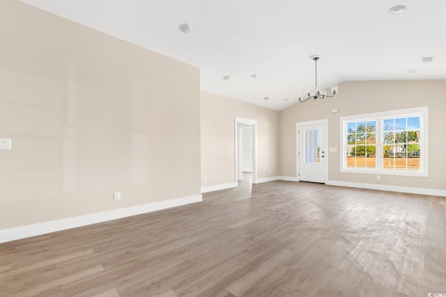 spare room with a chandelier, hardwood / wood-style flooring, and vaulted ceiling