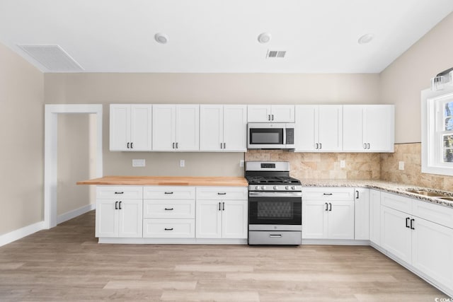 kitchen with wooden counters, sink, light wood-type flooring, white cabinetry, and stainless steel appliances