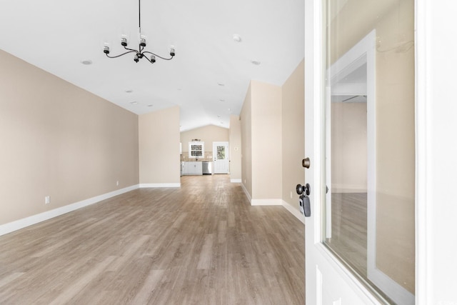 unfurnished living room with a notable chandelier, light wood-type flooring, and lofted ceiling