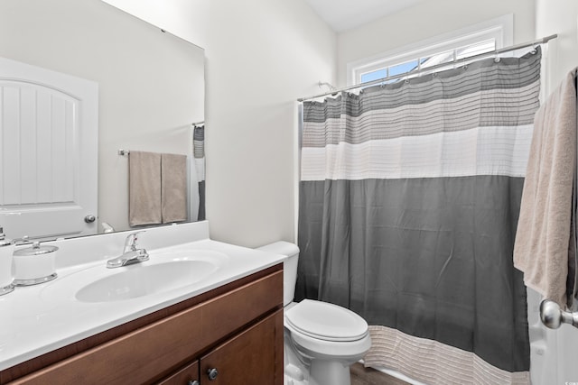 bathroom featuring vanity, curtained shower, and toilet