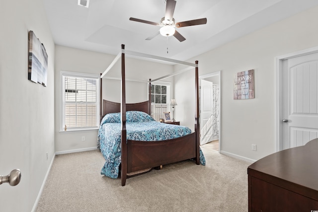 carpeted bedroom featuring a raised ceiling and ceiling fan