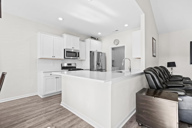 kitchen featuring sink, light hardwood / wood-style flooring, decorative backsplash, appliances with stainless steel finishes, and white cabinetry