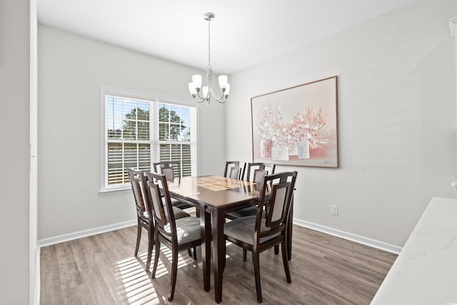 dining area with hardwood / wood-style flooring and an inviting chandelier