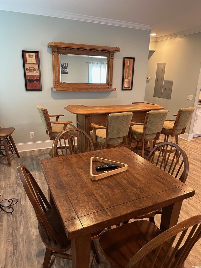 dining area featuring electric panel, hardwood / wood-style flooring, and ornamental molding