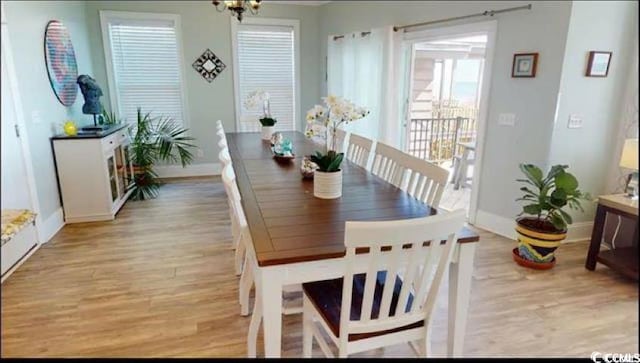 dining room with a notable chandelier, light wood finished floors, and baseboards