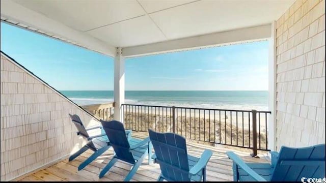 balcony with a water view and a view of the beach