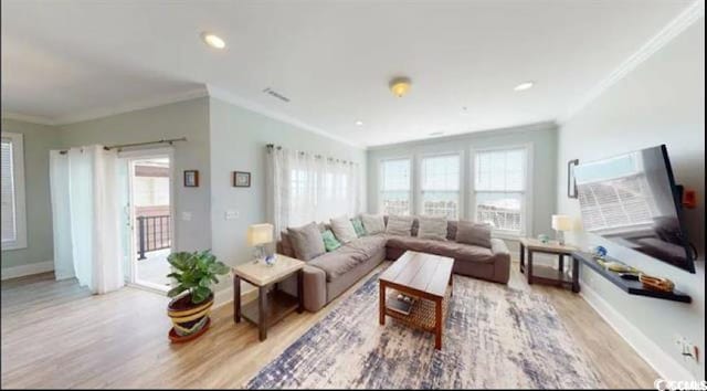 living room featuring baseboards, ornamental molding, light wood-type flooring, and a healthy amount of sunlight