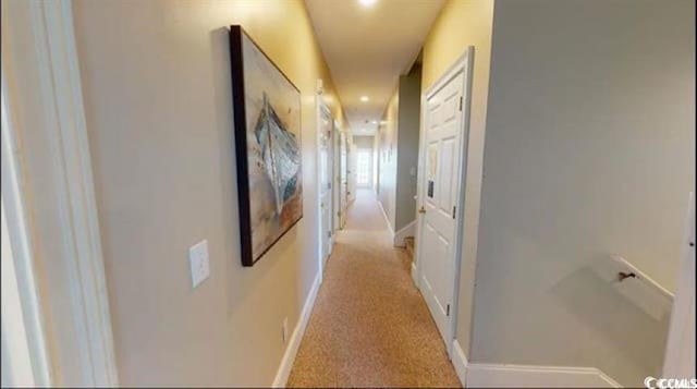 hallway featuring baseboards and light colored carpet