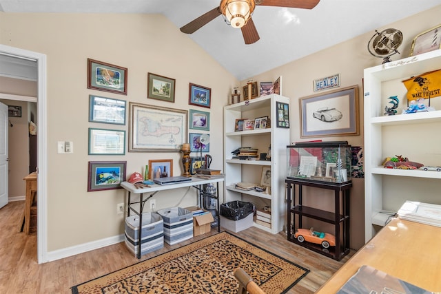 office space featuring built in shelves, vaulted ceiling, ceiling fan, and light wood-type flooring