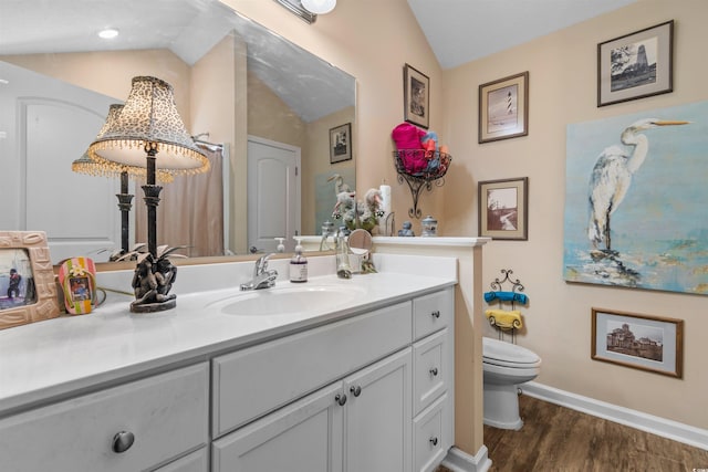 bathroom with vaulted ceiling, wood-type flooring, vanity, and toilet