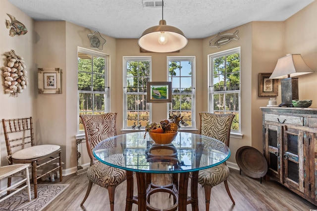 dining room with a textured ceiling and light hardwood / wood-style floors