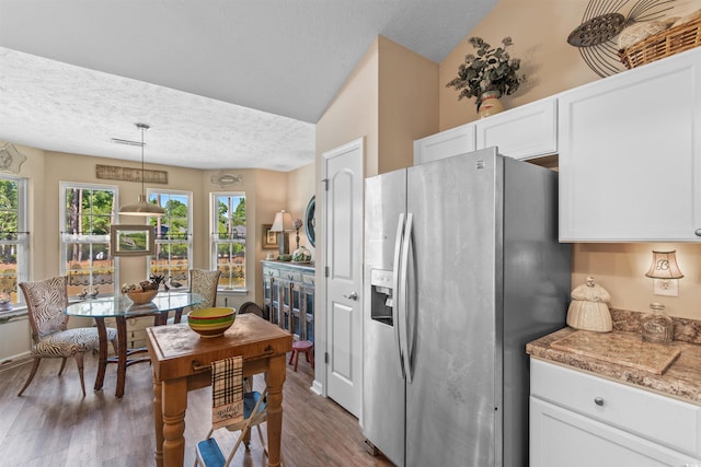 kitchen featuring dark hardwood / wood-style floors, pendant lighting, white cabinets, stainless steel fridge, and a textured ceiling