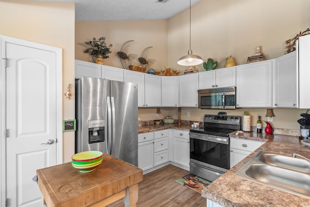 kitchen featuring hanging light fixtures, appliances with stainless steel finishes, sink, and white cabinets