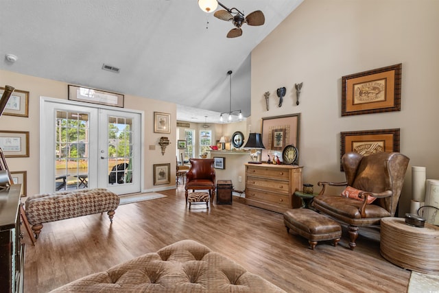 living area with ceiling fan, high vaulted ceiling, light hardwood / wood-style floors, and french doors