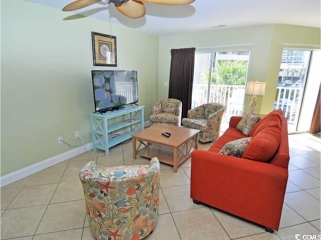 tiled living area with ceiling fan and baseboards