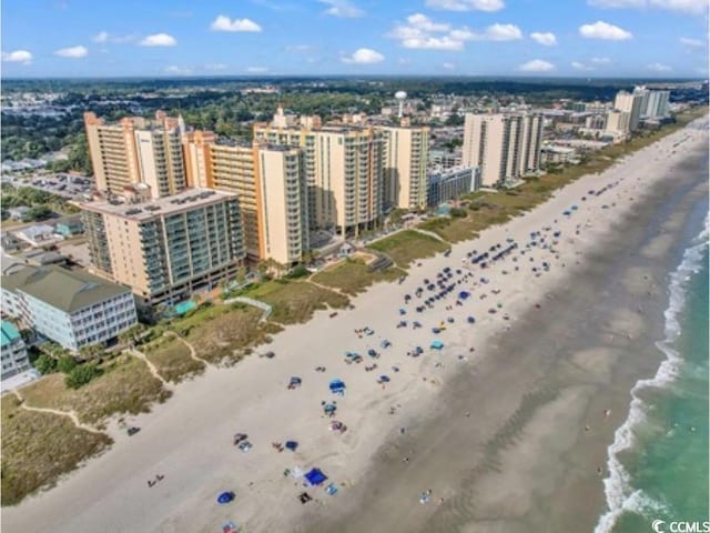 drone / aerial view featuring a water view, a view of the beach, and a city view