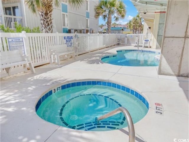 view of swimming pool featuring a hot tub, fence, and a patio